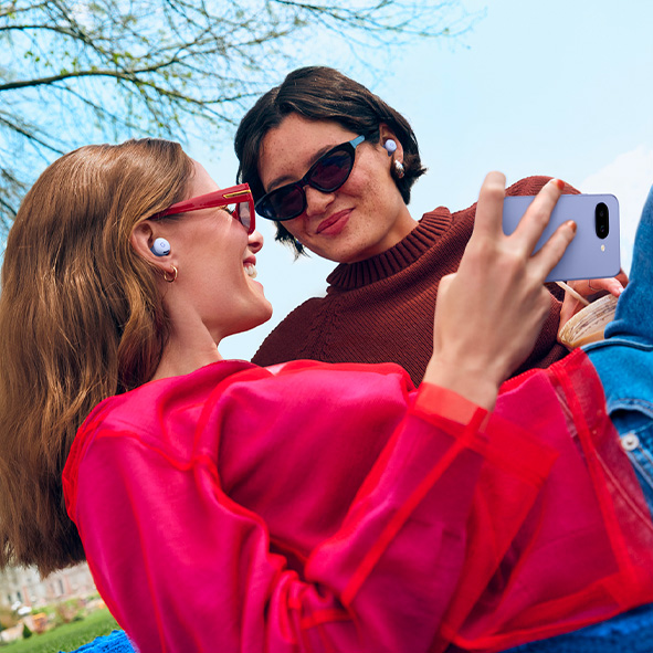 Picture of two women taking a selfie, wearing sunglasses and smiling with Pixel Buds 2a in their ears