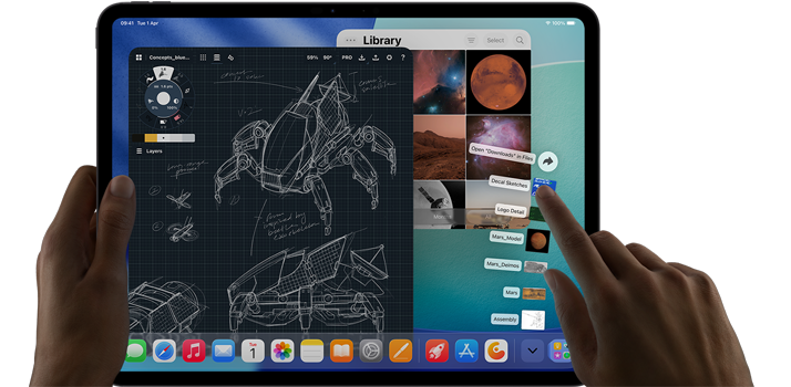 iPad Pro, space black colour, left hand holding device, right hand pointing gesturing to manipulate multiple open app windows, a drawing app with sketches of mechanical designs, photos library of planets and space images, downloads folder files fanned out