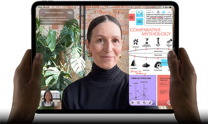 iPad Pro, front exterior, landscape orientation, space black colour, rounded corners, black display bezel, hands holding left and right sides, display showing a FaceTime conversation being live translated, and an educational app showing a presentation of Comparative Mythology with text, diagrams and handwritten notes
