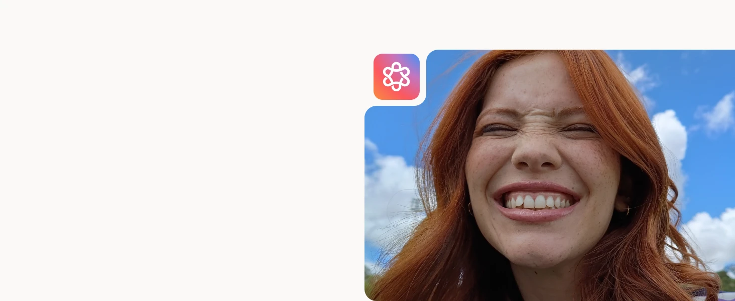 Close-up of a red-haired woman smiling broadly with eyes closed against a blue sky with clouds.